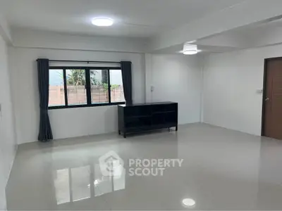 Spacious empty living room with large window and modern tile flooring