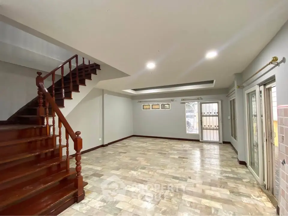 Spacious living room with wooden staircase and tiled flooring in modern home