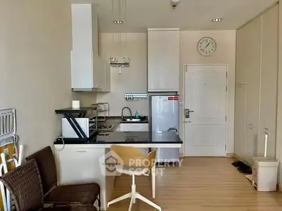 Modern kitchen with sleek cabinets and compact dining area in cozy apartment.