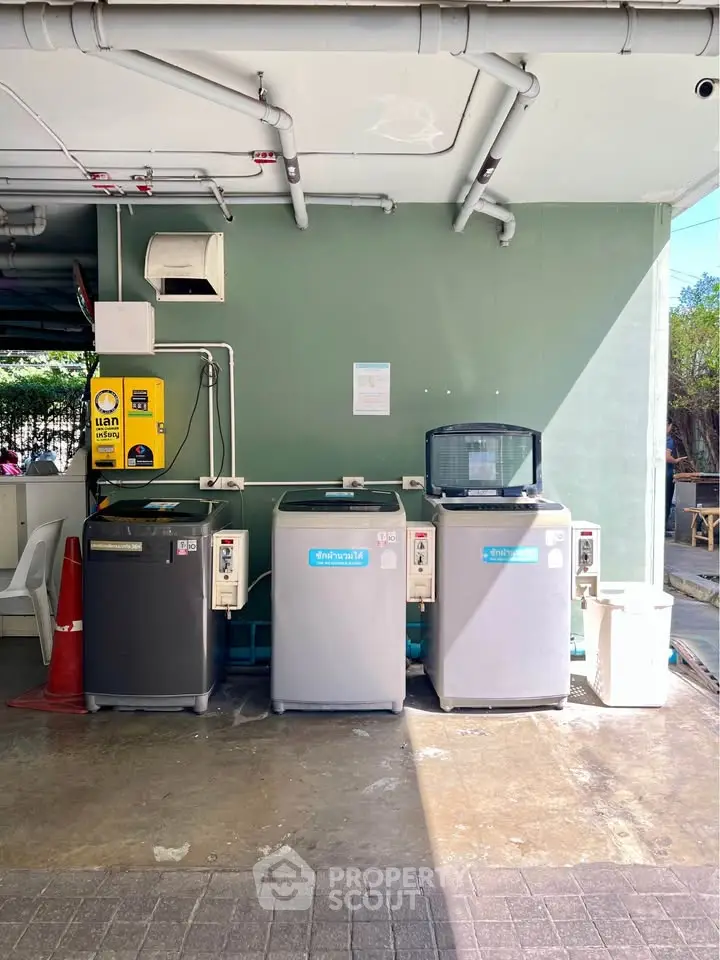 Outdoor laundry area with multiple washing machines and a payment station.