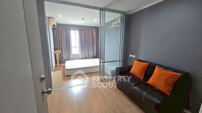Modern bedroom with glass partition and cozy seating area, featuring stylish decor and natural light.
