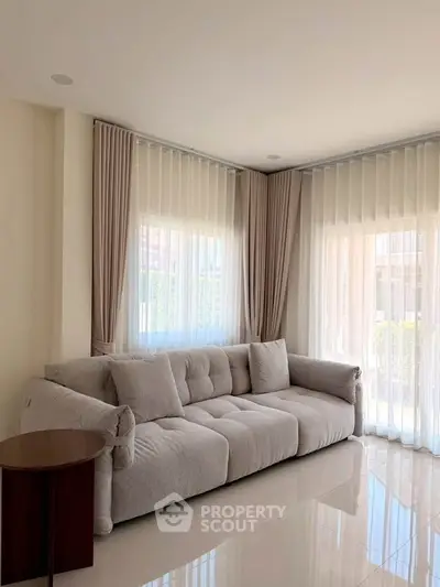 Spacious living room with plush sofa and large windows offering natural light.