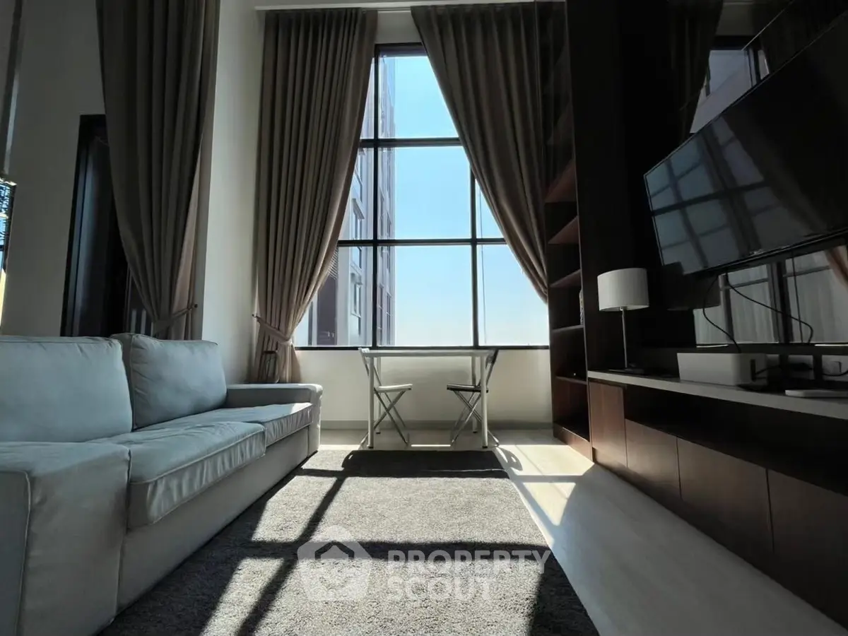 Modern living room with large windows and stylish decor, featuring a cozy sofa and a sleek TV setup.