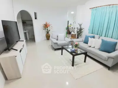 Spacious living room with modern decor and large TV, perfect for relaxation and entertainment.
