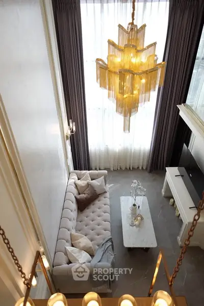 Luxurious high-ceiling living room with elegant chandelier and plush sofa