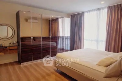Spacious bedroom with large mirrored wardrobe and natural light