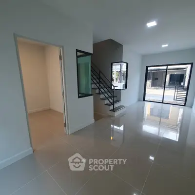 Spacious modern living room with sleek staircase and large windows for natural light.