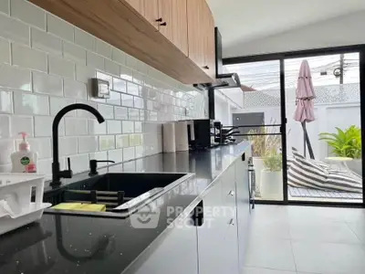 Modern kitchen with sleek black countertop and open layout leading to patio