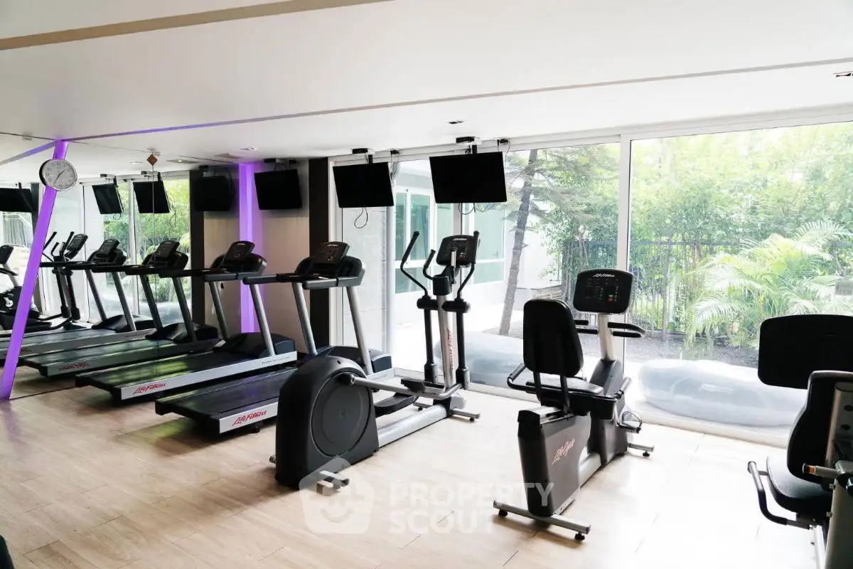 Modern gym with treadmills and exercise bikes in a bright, spacious setting.