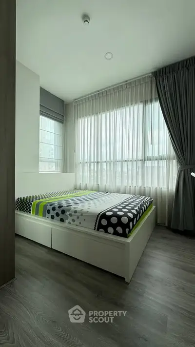 Modern bedroom with large window and stylish decor in a contemporary apartment.