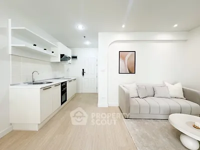 Modern open-layout living room with sleek kitchen, cozy sofa, and stylish decor in a bright, inviting space.
