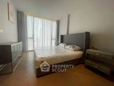 Spacious bedroom with modern furnishings and large window for natural light.