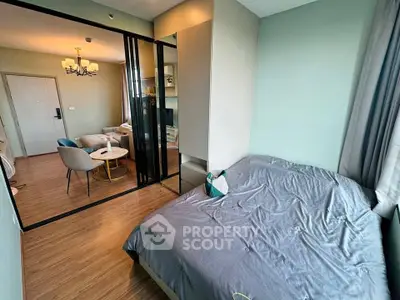 Modern bedroom with sliding glass doors leading to a cozy living area, featuring stylish decor and warm lighting.