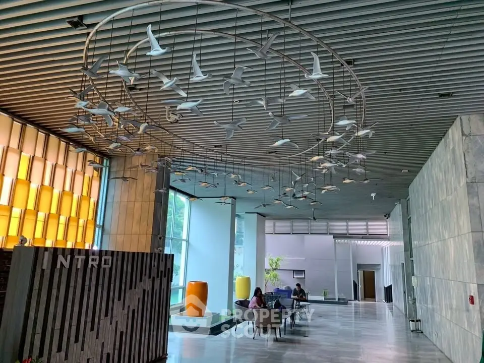 Modern building entrance with artistic ceiling decor and seating area