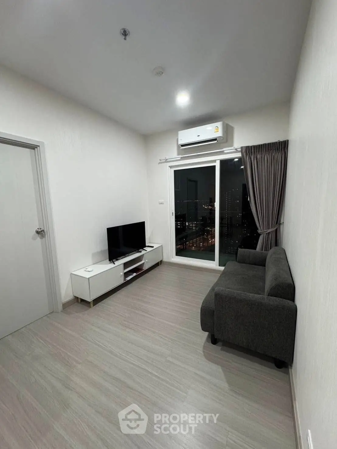 Modern living room with city view, featuring sleek furniture and air conditioning.