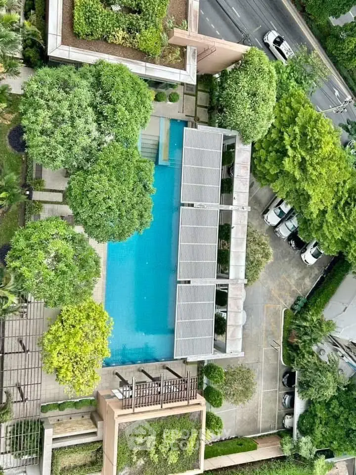 Stunning aerial view of a luxurious residential pool surrounded by lush greenery and modern architecture.
