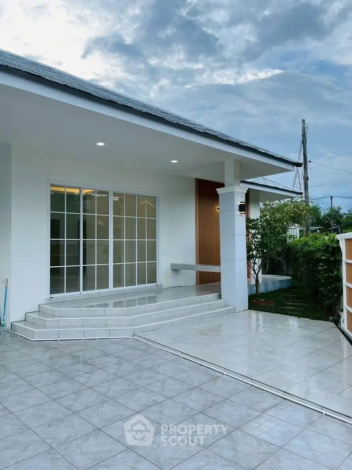 Modern house exterior with spacious tiled patio and large glass doors.