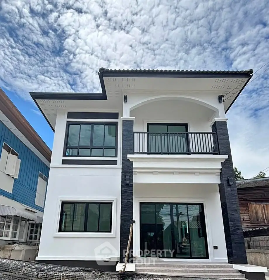 Modern two-story house with sleek black and white exterior under a vibrant blue sky.