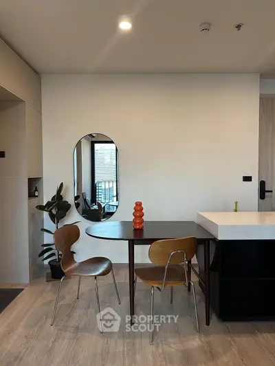 Modern dining area with stylish chairs and table, featuring a sleek mirror and contemporary decor.