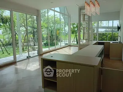 Spacious modern living room with large windows and garden view, featuring elegant lighting and open layout.