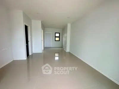 Spacious empty room with glossy tiled floors and neutral walls, ready for customization.