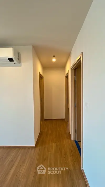 Modern hallway with wooden flooring and air conditioning unit in a contemporary home.