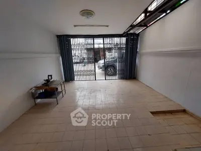 Spacious tiled room with large window and metal gate, ideal for versatile use.