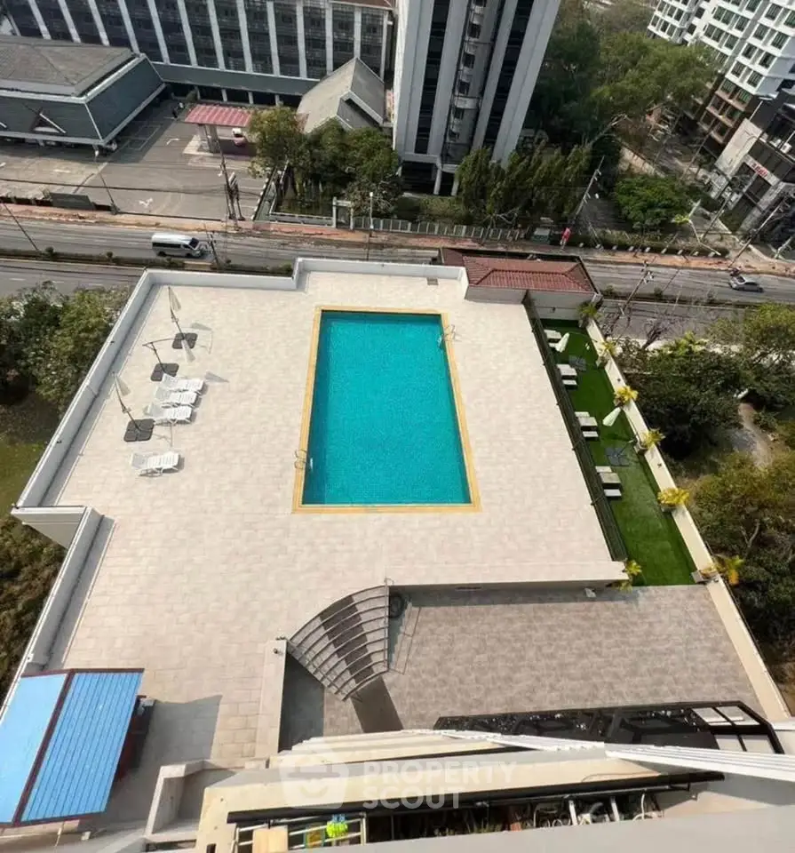 Stunning aerial view of a modern apartment complex with a large swimming pool and spacious deck area.