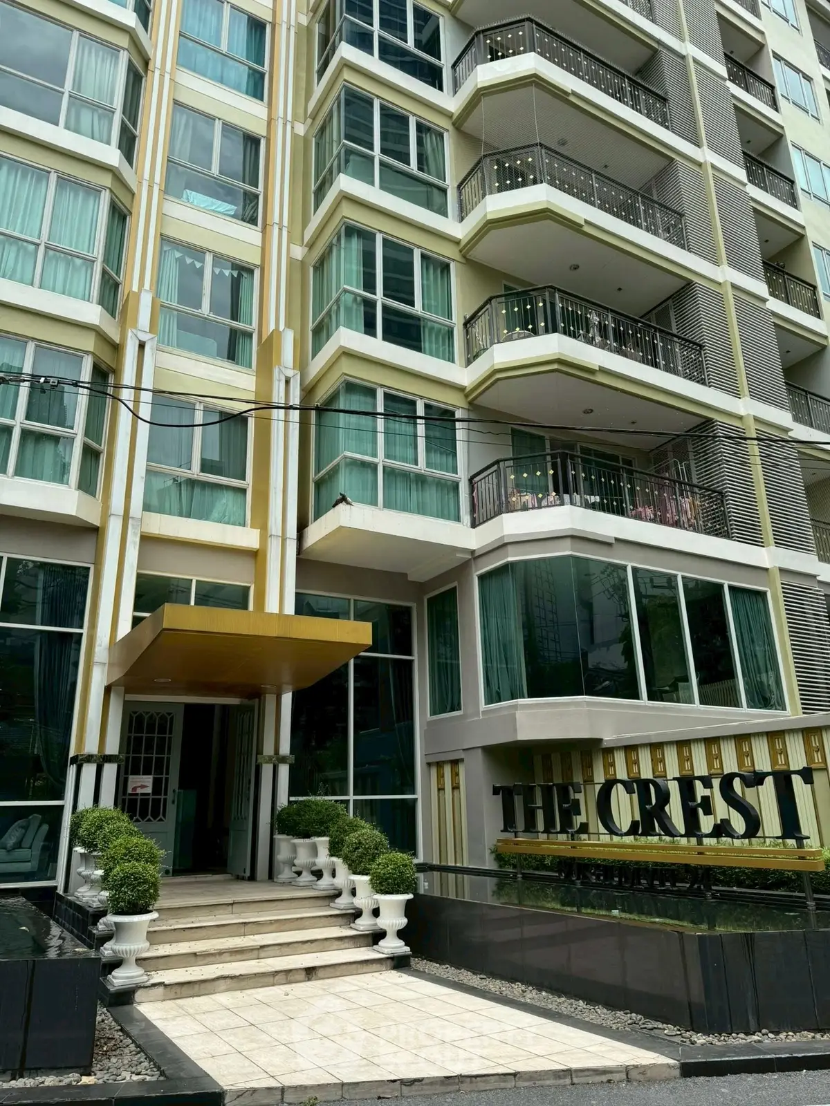 Modern high-rise building exterior with balconies and elegant entrance at The Crest.