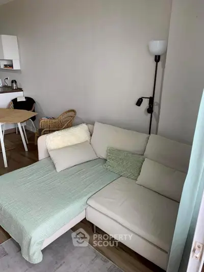 Cozy living room with modern sectional sofa and dining area in open layout apartment.