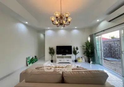 Spacious living room with elegant chandelier and modern decor, featuring large sliding glass doors opening to a patio.