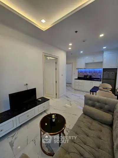 Modern living room with sleek design and open kitchen layout, featuring elegant marble flooring and cozy seating.