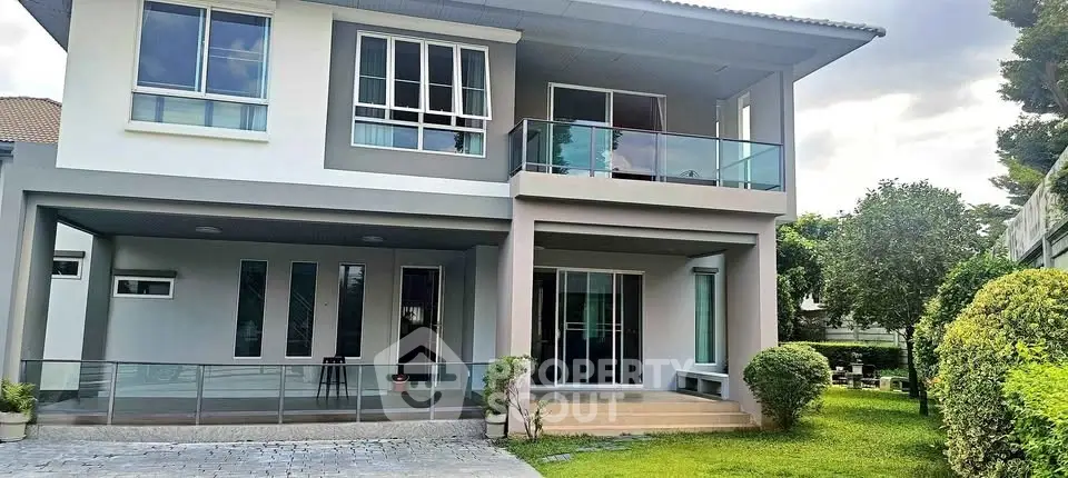 Modern two-story house with large windows and lush garden, perfect for family living.