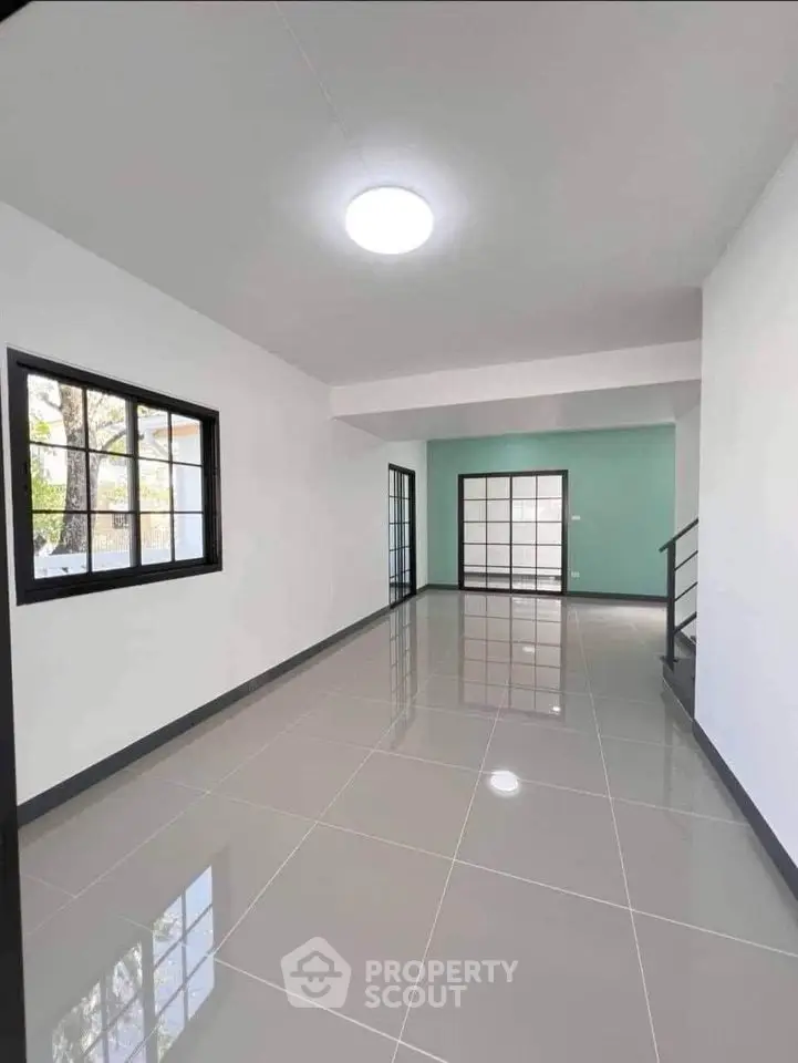 Spacious modern living room with glossy tiled floors and large windows.