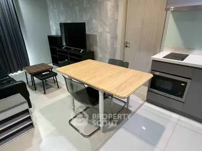 Modern open-layout living room with sleek kitchen and dining area, featuring contemporary furniture and appliances.
