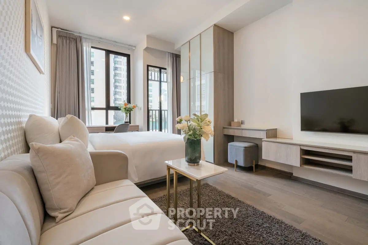 Modern studio apartment with stylish decor and large windows offering city views.