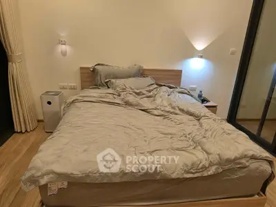Cozy bedroom with modern lighting and wooden flooring, perfect for relaxation.