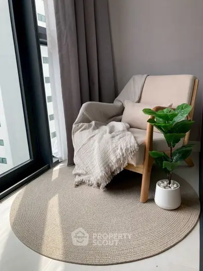Cozy reading nook with armchair and plant by large window in modern apartment.