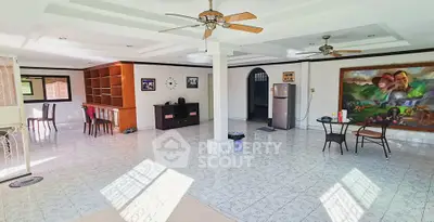 Spacious open-plan living room with ceiling fans and tiled flooring, perfect for entertaining.