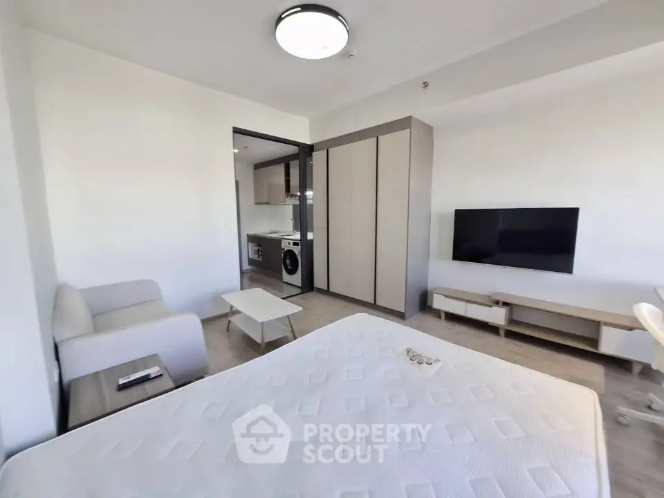 Modern studio apartment with open layout, featuring a cozy living area and sleek kitchen appliances.