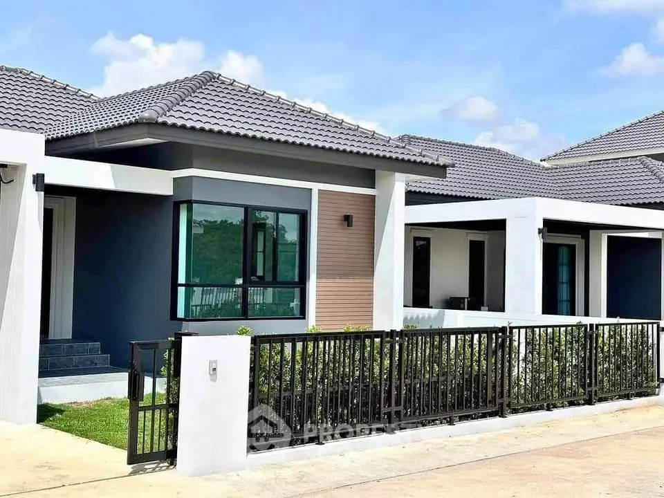 Modern single-story house with sleek design and gated entrance in a suburban neighborhood.