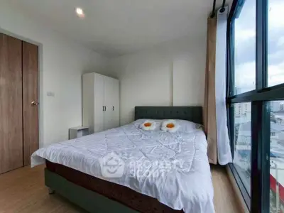 Cozy bedroom with large windows offering city views and modern furnishings.