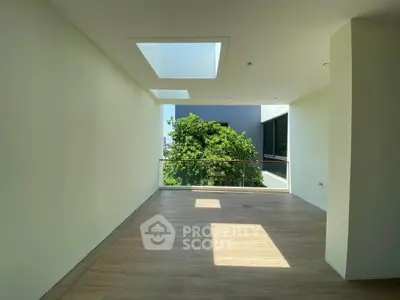 Spacious room with skylights and balcony overlooking lush greenery, perfect for modern living.