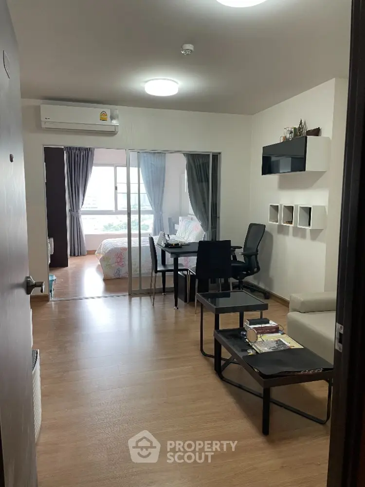 Modern apartment interior with open living and dining area, featuring sleek furniture and natural light.