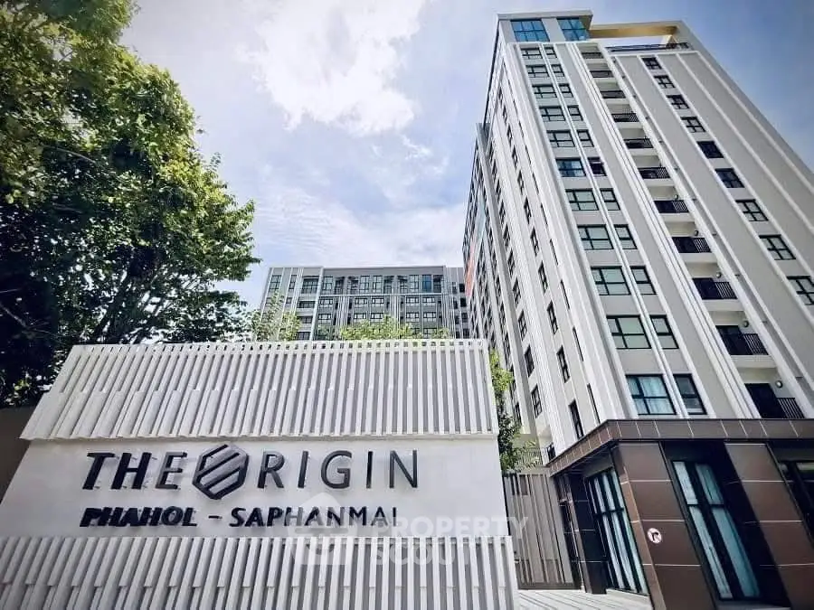 Modern high-rise condominium building with sleek design and lush greenery.
