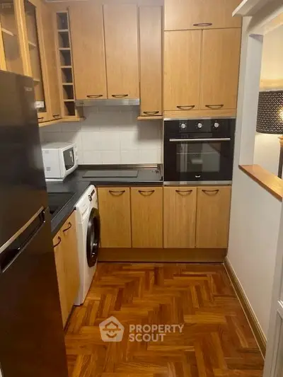 Charming kitchen with wooden cabinets, modern appliances, and parquet flooring.