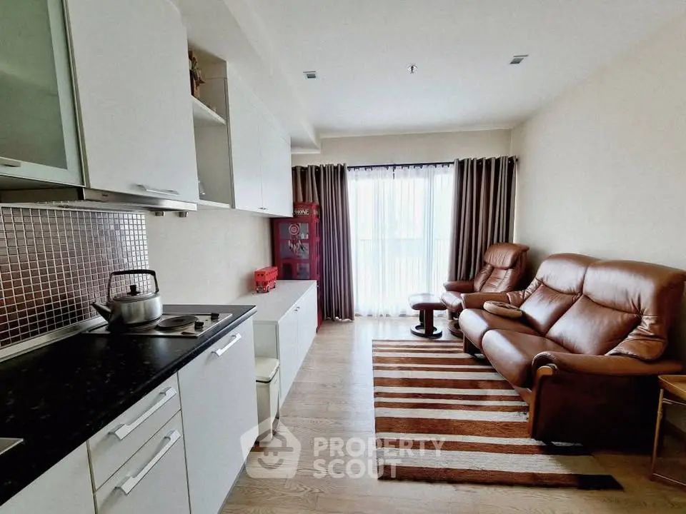 Modern living room with open kitchen, leather seating, and natural light.