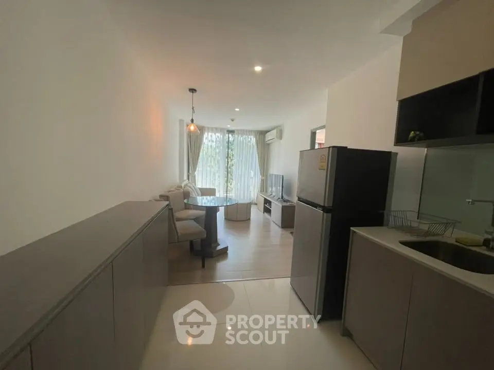 Modern living room with open kitchen, featuring sleek furniture and natural light.