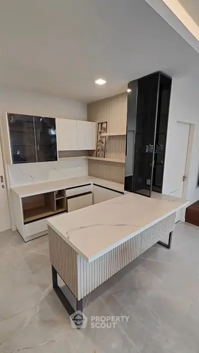 Modern kitchen with sleek cabinetry and marble countertops, featuring an open layout and contemporary design.