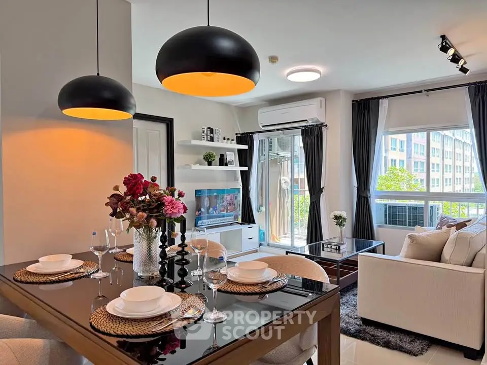 Modern living room with dining area, stylish lighting, and large windows offering natural light.